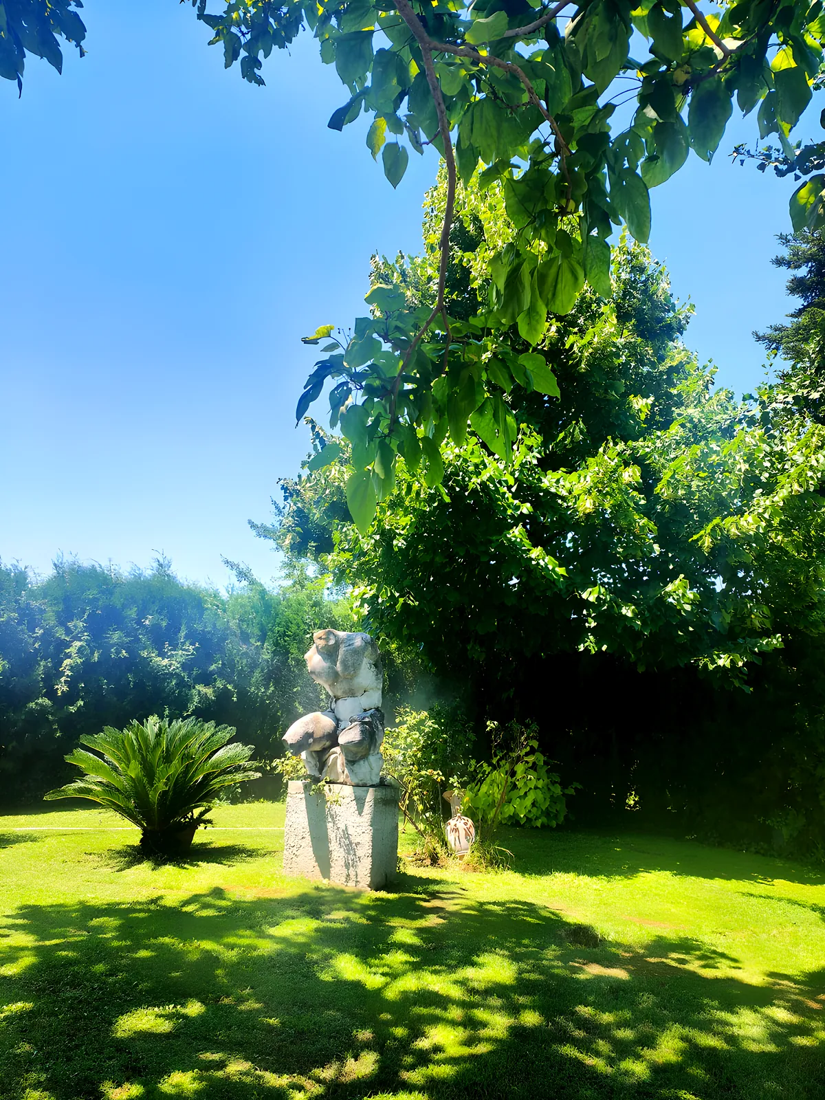 Una scultura in pietra tra le siepi del giardino